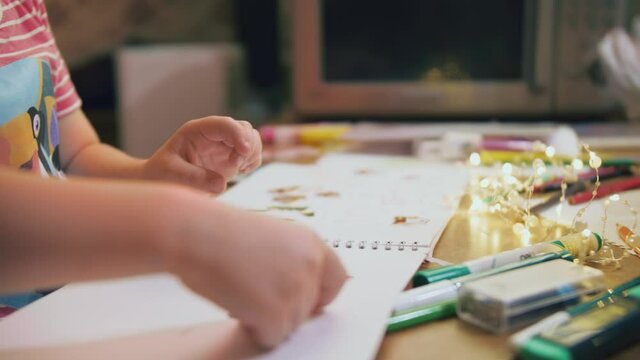 Mother and son of preschool age are preparing for the New Year's holiday at home close-up carefully glues vinyl stickers into the album, which is a creative, educational game. 