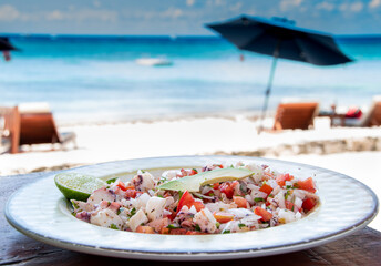 plate of seafood ceviche in the foreground, beach in the background