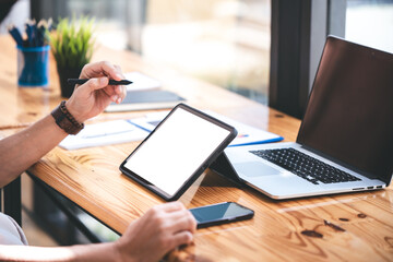hand image of a male freelancer holding a blank screen tablet in his modern workplace