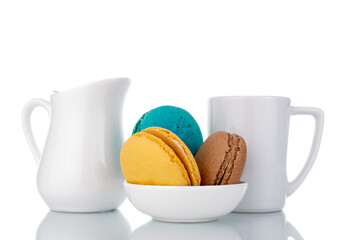 Three sweet macaroons with white ceramic dishes, close-up, isolated on white.