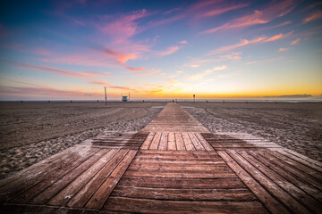 Wooden boardwalk on the sand in Santa Monica beach at sunset
