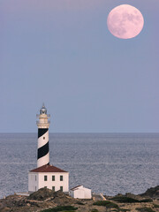 FARO DE FAVARITX EN MENORCA CON LA LUNA SALIENDO POR DETRAS

