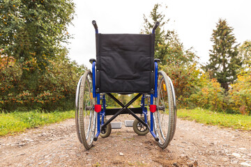 Fototapeta na wymiar Empty wheelchair standing on road waiting for patient services. Wheel chair for people person with disability parked outdoor. Accessible for person with disability. Health care medical concept