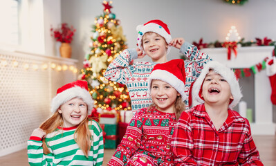 Happy children sitting in the living room at home in christmas pajamas