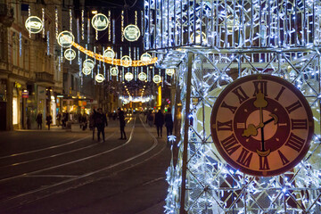  Beautiful Christmas decorations with famous Clock Tower on Herrengasse street, at night, in the city center of Graz, Steiermark, Austria. Long exposure for the movement