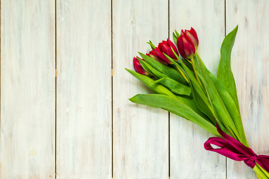 Bouquet of red tulips on a white wooden background with place for text. Valentine's day concept.