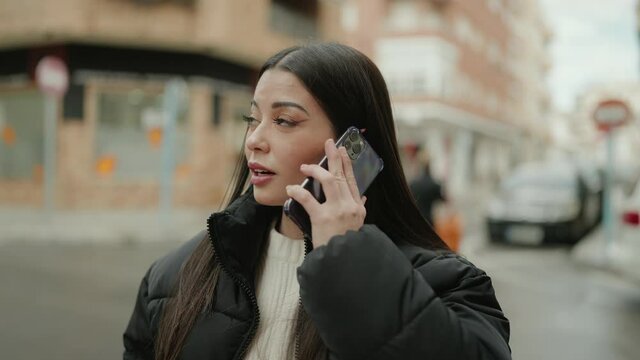 Young hispanic woman smiling confident talking on the smartphone at street