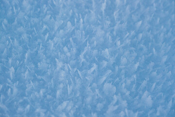 Snow texture with snowflakes close-up. Blue macro image of an abstract snowdrift. Crystal snow minimal texture pure. Winter landscape background.