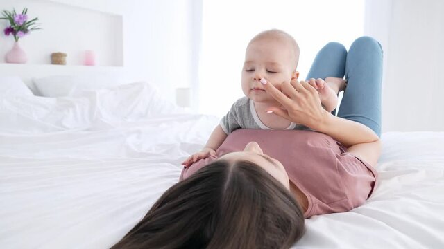 Sweet nanny lady playing carrying baby boy laughter comfort bed indoors
