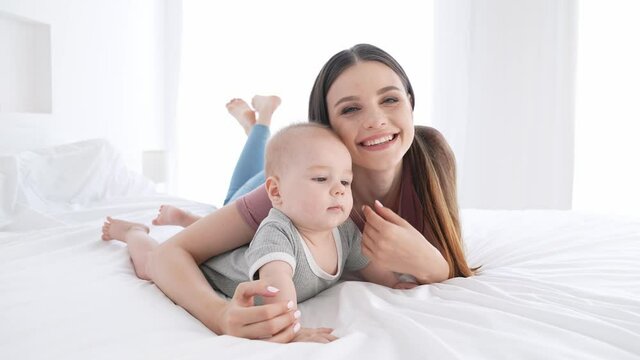 Cute sweet mommy lying bed cuddle baby boy childcare indoors