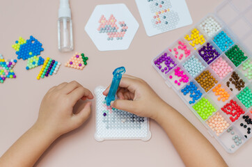 Children's educational game aqua mosaic, a small child inserts multicolored beads into the pattern...