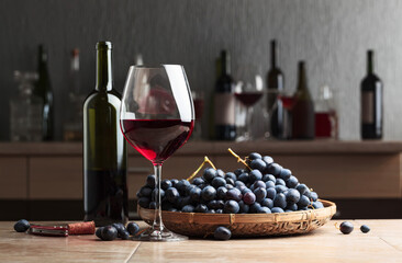 Glass and bottle of red wine and blue grapes.