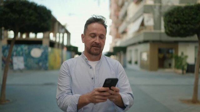 Young caucasian man smiling confident using smartphone at street