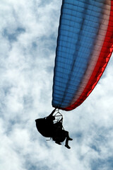 people paragliding against the light in cloudy skies