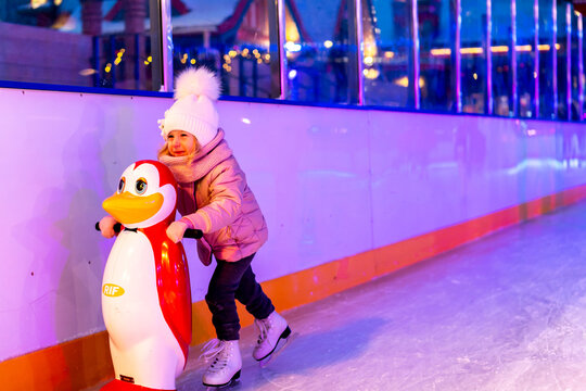 A Little Girl Is Skating On An Ice Rink, Holding On To A Support, A Child Is Learning To Skate, Winter Entertainment For Children