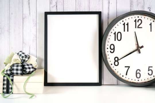 Wall art print frame product mockup. New Year's Eve farmhouse theme SVG craft product mockup styled with large rustic clock, stack of books and buffalo plaid ribbon against a white wood background.
