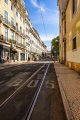 Fototapeta na wymiar Krajobraz miejski, ciasne uliczki, tramwaje i tory tramwajowe w mieście Lizbona, Portugalia.