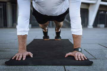 Athlete standing in plank pose, training outdoors