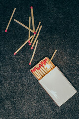 Matches in a box, dark background. burning match. Close-up shot. Matches in an open box of matches on a fabric felt backing. matches on a black background.scattered matches next to the box