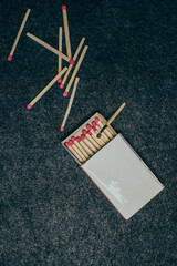 
Matches in a box, dark background. smoldering match. Close-up shot. Matches in an open box of matches on a fabric felt backing.
scattered matches next to the box.matches on a black background