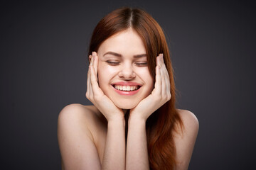 Naklejka premium pretty red-haired woman naked shoulders posing dark background