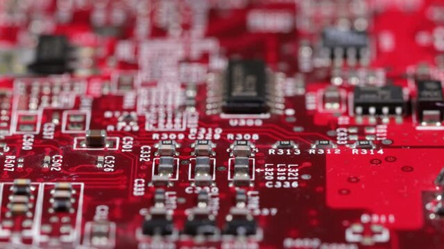 close up of red computer circuit board with chips transistors and white markings