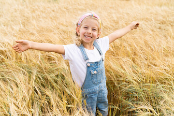 Naklejka na ściany i meble Little blonde girl in the field of rye, grain harvest
