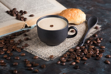 Cappuccino and croissant on the table. The concept of morning breakfast. Coffee beans scattered on the table.