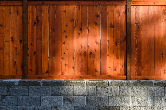 Brand new wooden fence built on a concrete block retaining wall, as a background
