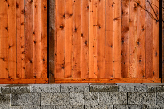 Brand new wooden fence built on a concrete block retaining wall, as a background
