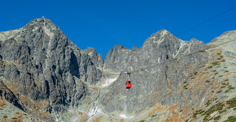 A red cable car on its way from Skalnate pleso to Lomnicky peak. Red gondola moving up to Lomnica peak in High Tatras Mountains. Slovakia.
