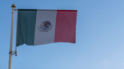 National flag of Mexico on a flagpole in front of blue sky with sun rays and lens flare. Diplomacy concept.