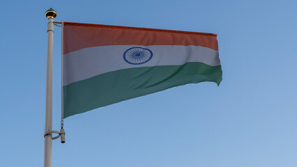 National flag of India on a flagpole in front of blue sky with sun rays and lens flare. Diplomacy concept.