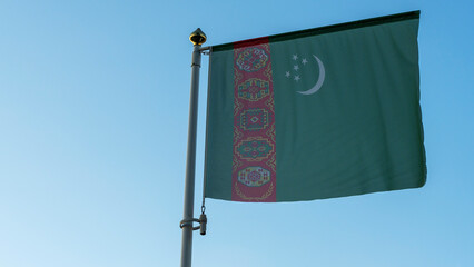 National flag of Turkmenistan on a flagpole in front of blue sky with sun rays and lens flare. Diplomacy concept.