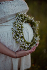 wreath of flowers on the pregnant woman belly