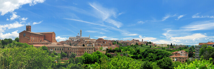 Fototapeta na wymiar Cityscape Of Siena In Tuscany Italy With The Famous Cathedral And San Domenica Church On A Beautiful Spring Day With A Blue Sky And A Few Clouds