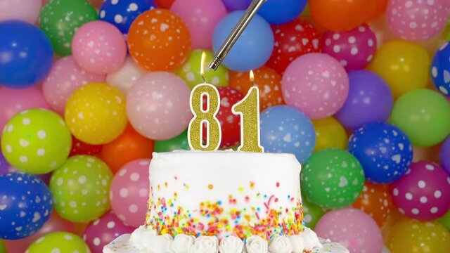 Cake with burning candles number 81. A tasty celebration cake on a bright festive background of colorful balloons.