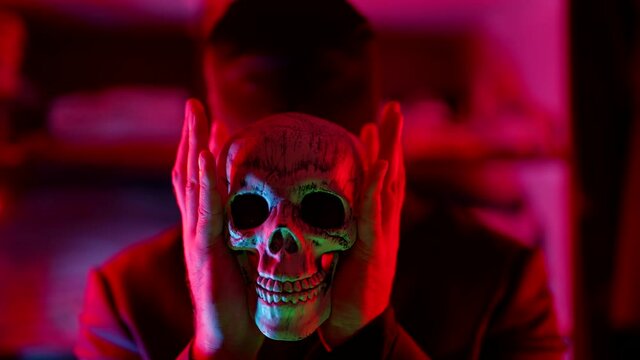 scary movie and horror, madman is playing with human skull in gloomy darkness