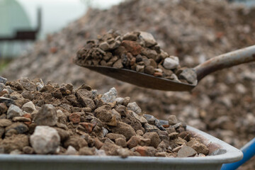 Trolley for building material. Trolley for building material. Load the cart with crushed stone using a shovel. Concept: construction, road repairs, sale of crushed stone, backgrounds and textures