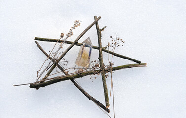 crystal mineral and pentagram made of tree branches on snow natural background. Gemstones for...