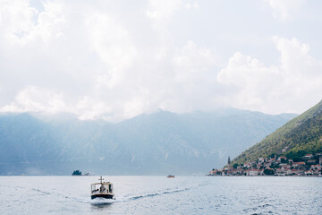 Motor boat sails along the Kotor Bay against the backdrop of the town of Perast. Montenegro