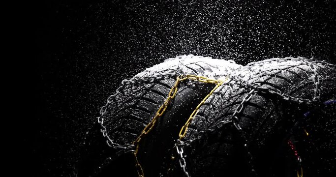 Winter Car tires with snow flakes and chains on black background. Winter season. Slow motion 4k video