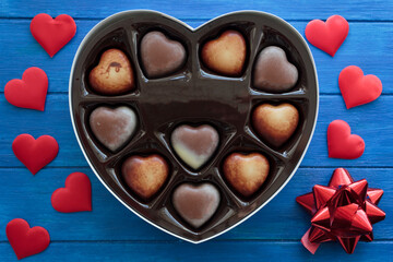 Top view of heart chocolates in gift box on blue wooden table