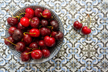 Ripe red cherries bowl on portuguese tiles background