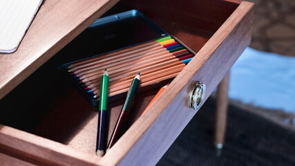 High angle view of handcrafted wooden pencils inside an oak wood desk drawer.