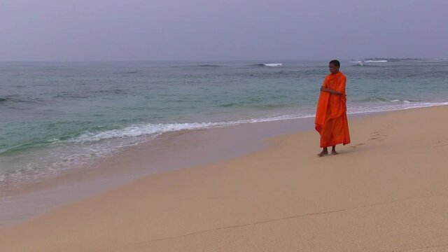 Monk saffron robe walking beach sri lanka