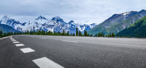 Asphalt road and snow mountain under blue sky. Highway and mountain background.