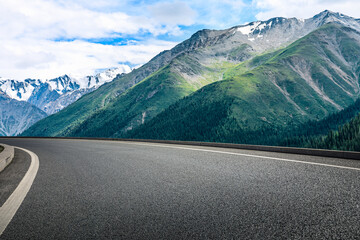 Asphalt road and snow mountain under blue sky. Highway and mountain background.