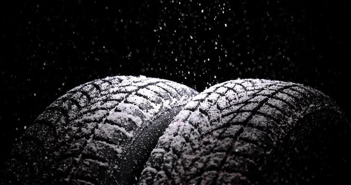 Winter Car tires with snow flakes on black background. Winter season. Slow motion 4k video