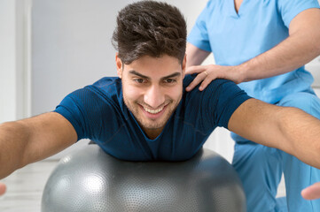 Physiotherapist helps handsome young patient with pilates exercises. High quality photo